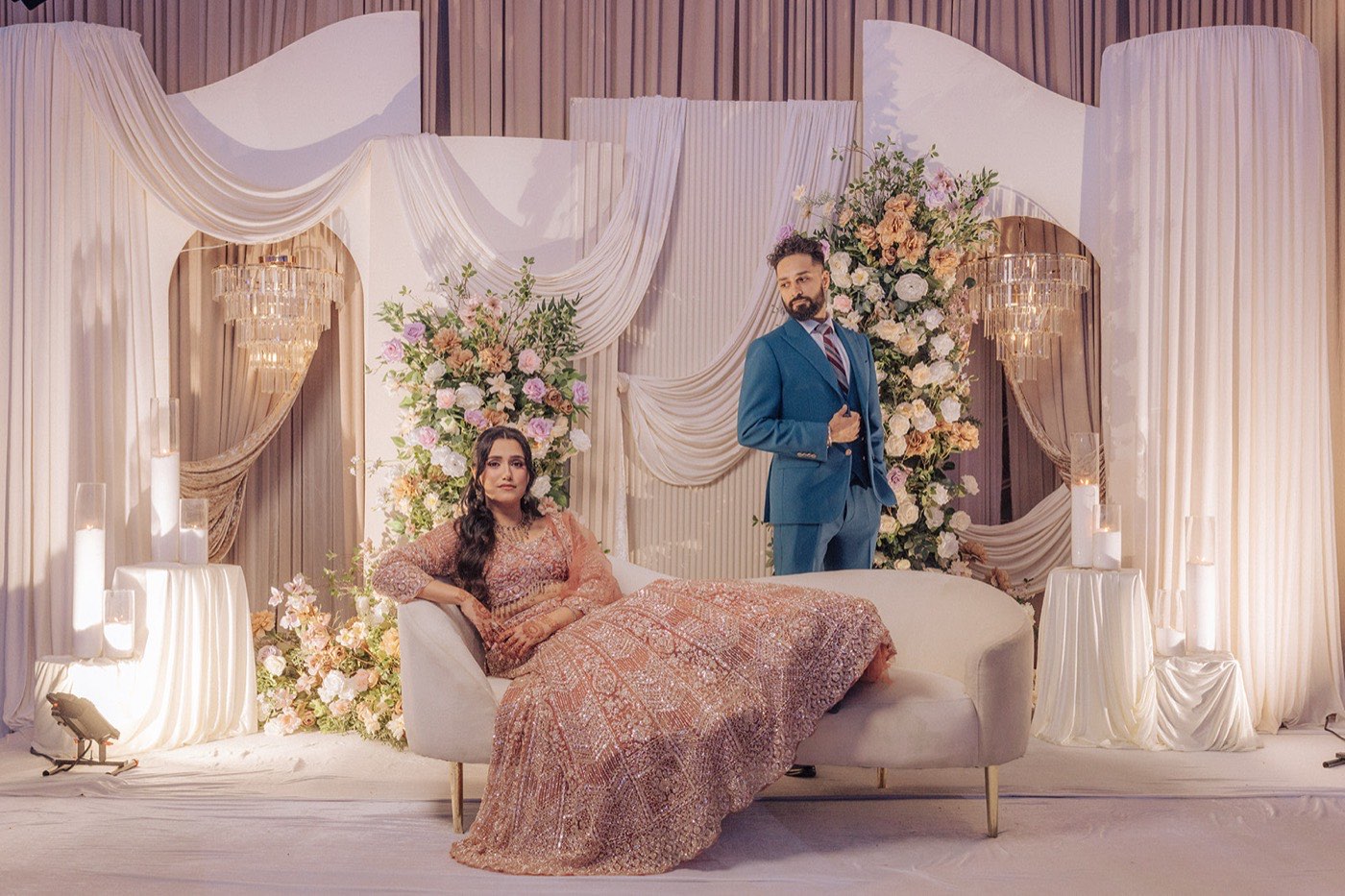 Navjot and Lovedeep engagement — the couple on a blush chaise amid a floral stage at Noor Convention Centre, Brampton