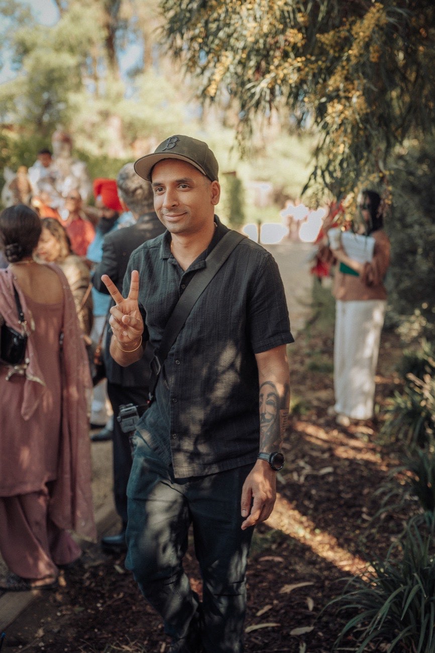 Bobby, the photographer behind Still Motion Frames, holding up a peace sign at a South Asian wedding